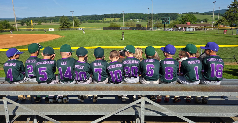 Youth baseball team meeting with their coach at the ball field